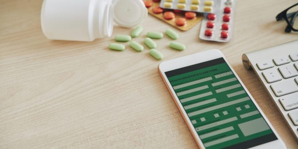 Smartphone with heath insurance application and tablets on table